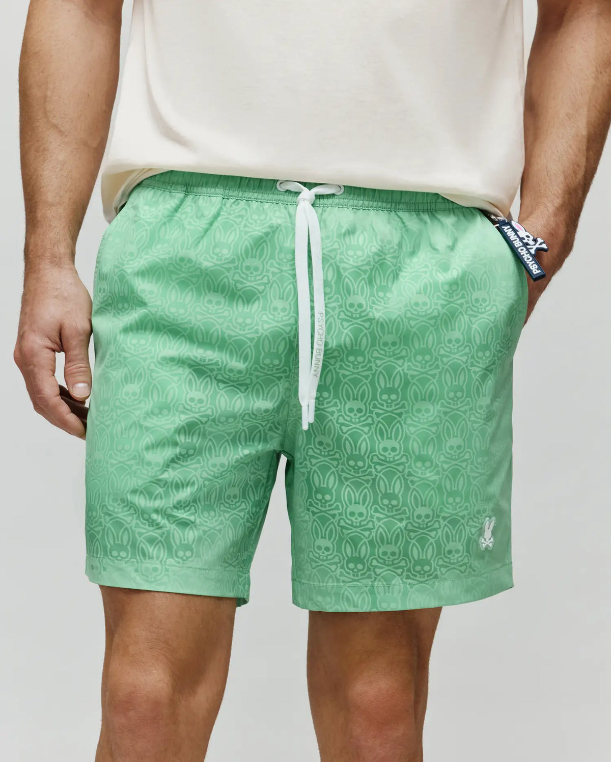 Mens Samos Hydrochromic Printed Swim Trunk in light green, featuring an all-over subtle bunny skull pattern, white drawstrings with Psycho Bunny text, and a small white embroidered bunny skull logo.