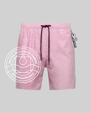 Psycho Bunny MENS SAMOS HYDROCHROMIC PRINTED SWIM TRUNK - B6W453F200: Light pink swim trunks with subtle bunny pattern, mesh lining, dark drawstring, and bunny keychain. Water-activated hydrochromic fabric. White circular graphic overlay. Light gray background.