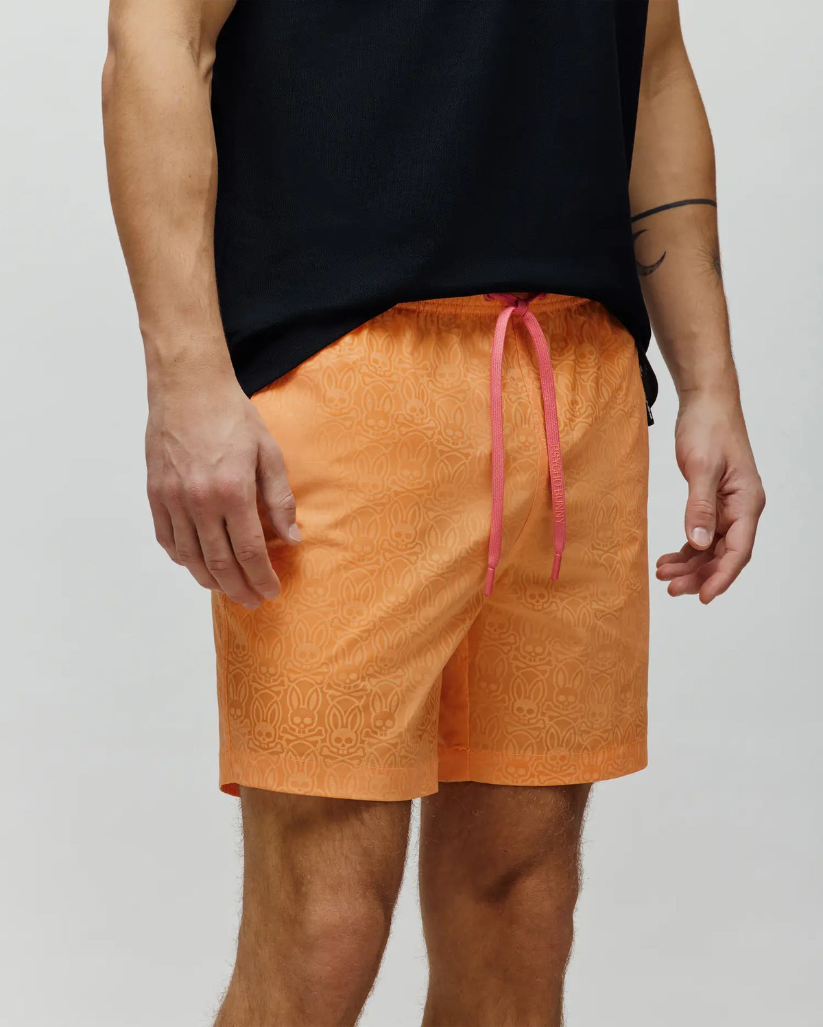 Mens Samos Hydrochromic Printed Swim Trunk in vibrant orange, featuring a subtle repeating hydrochromic Psycho Bunny skull logo pattern and contrasting pink drawstrings with Psycho Bunny branding, in a classic fit with smooth fabric.