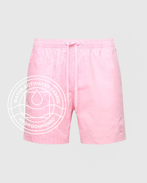 The Psycho Bunny MENS SAMOS HYDROCHROMIC PRINTED SWIM TRUNK (B6W453F200) features pink swim shorts with a subtle bunny pattern, drawstring waist, and a “Water Activated Fabric Hydrochromic” label for innovative style. Displayed on a light background.