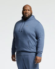 A man wears a blue Psycho Bunny MENS BIG AND TALL LEVY ESSENTIAL FLEECE HOODIE (B9H859D200) and matching sweatpants, facing the camera against a plain white background.