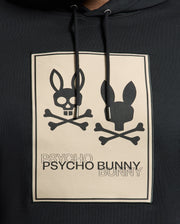 The Psycho Bunny Men's Big and Tall Monroe Twill Patch Fleece Hoodie features a black design with two bunny skull and crossbones graphics, complemented by the "PSYCHO PSYCHO BUNNY BUNNY" phrase in alternating shades, finished with a signature patch applique.