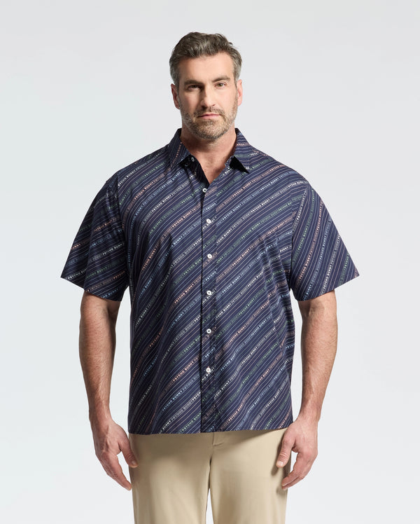 A man sports a Psycho Bunny MENS BIG AND TALL RENMARK STRETCH POPLIN WOVEN SHIRT in blue diagonal stripes, stylishly paired with beige pants against a light backdrop.