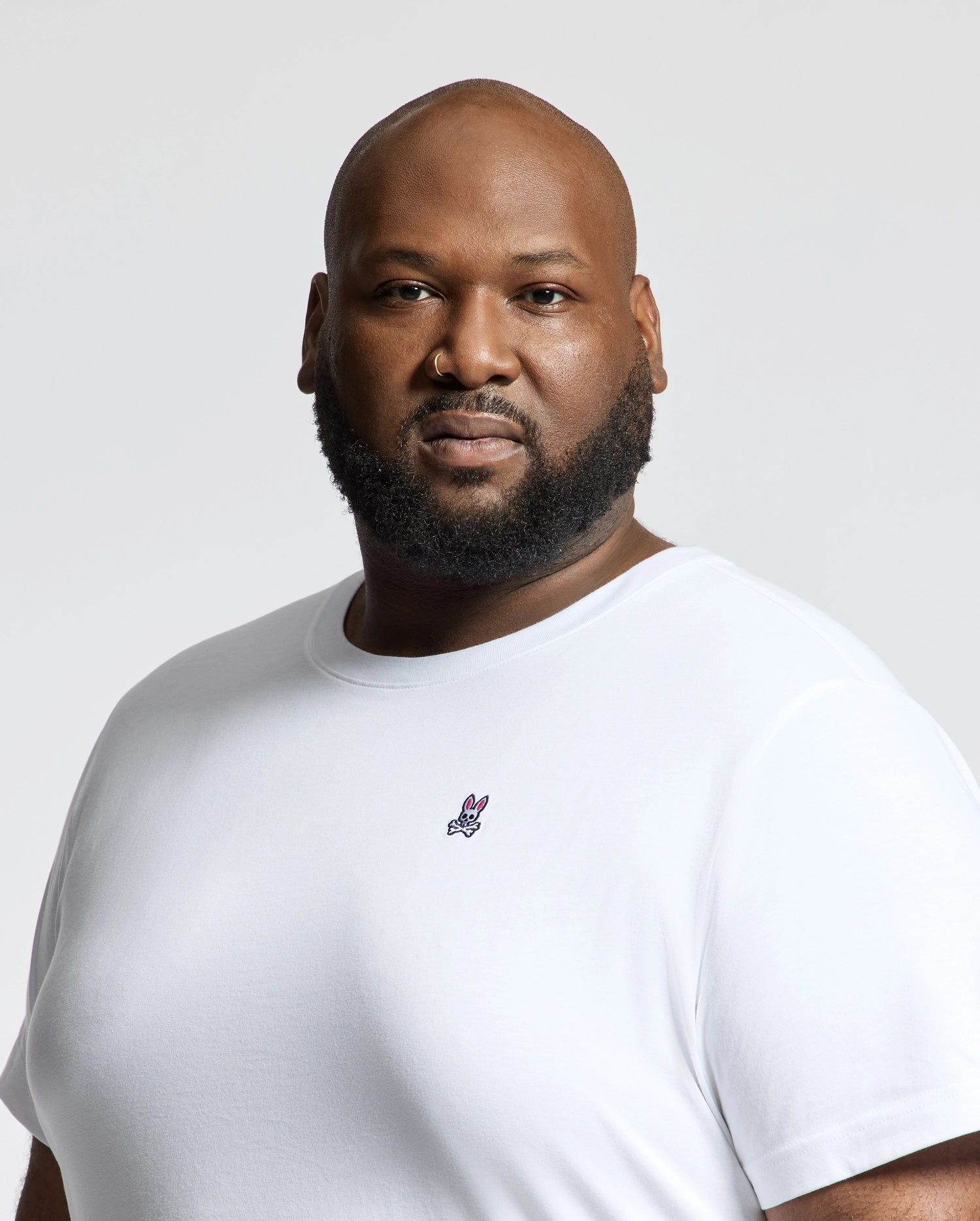 A bearded man in a Psycho Bunny MENS BIG AND TALL CLASSIC CREW NECK TEE - B9U014CRPC, crafted from soft Pima cotton with a small embroidered logo, poses against a plain light background—an essential for every man's wardrobe.