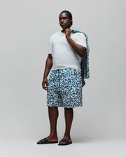 Mens Big And Tall Josh All Over Bunny Swim Trunk in a relaxed fit, featuring a white base with an all-over teal pixelated Psycho Bunny skull logo pattern and a small pink embroidered bunny logo on the left leg.