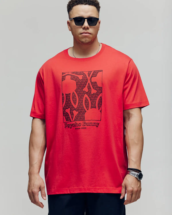 A man stands against a plain background wearing black sunglasses, dark pants, a wristwatch, and the Psycho Bunny MENS BIG AND TALL GLENN GRAPHIC TEE - BT0200006 in red with a bold Bunny graphic and "Psycho Bunny Since 2005" print.