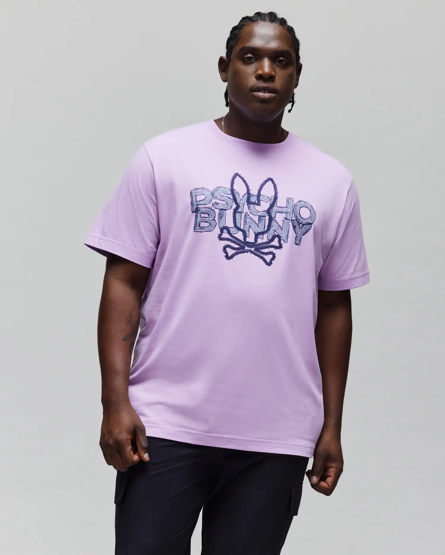 Mens Big And Tall Herman Graphic Tee, a relaxed fit lavender smooth jersey t-shirt featuring a large central distressed dark purple Psycho Bunny skull and crossbones logo graphic.