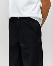 A person wears a white t-shirt tucked into high-waisted, loose-fit Psycho Bunny KIDS MATHIEU COMMUTER PANT (KB0600002) with a classic cut and small bunny embroidery on the pocket. Their face is hidden with hands behind their back.