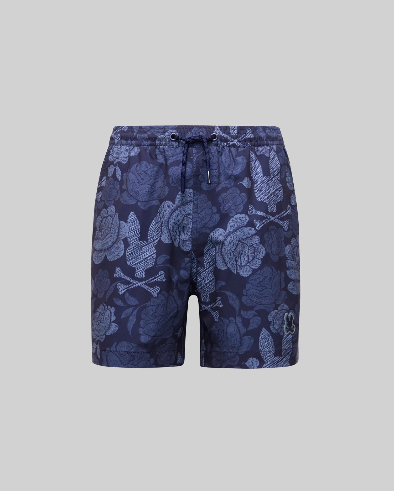 Psycho Bunny KIDS ROWEN SWIM TRUNK (KB1000009) in navy with light blue floral and leaf print, quick-dry fabric, drawstring waist, and small embroidered logo on the left leg, shown on a plain gray background.