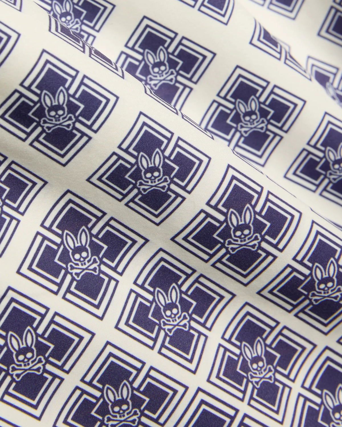 Kids Tobias Swim Trunk in cream with an all-over navy blue geometric square pattern featuring repeated Psycho Bunny skull logos on smooth woven fabric. (6)