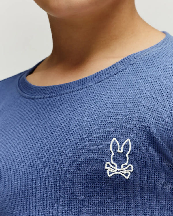 Kids Noe Long Sleeve Waffle Tee, a vibrant blue classic fit waffle knit shirt featuring a crisp white embroidered Psycho Bunny skull logo on the left chest.