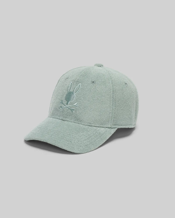 The KIDS KELVIN TOWEL TERRY BASEBALL CAP (KO1500007) by Psycho Bunny offers summer comfort with its light green textured design and embroidered Bunny head above crossed bones, shown on a plain light gray background.