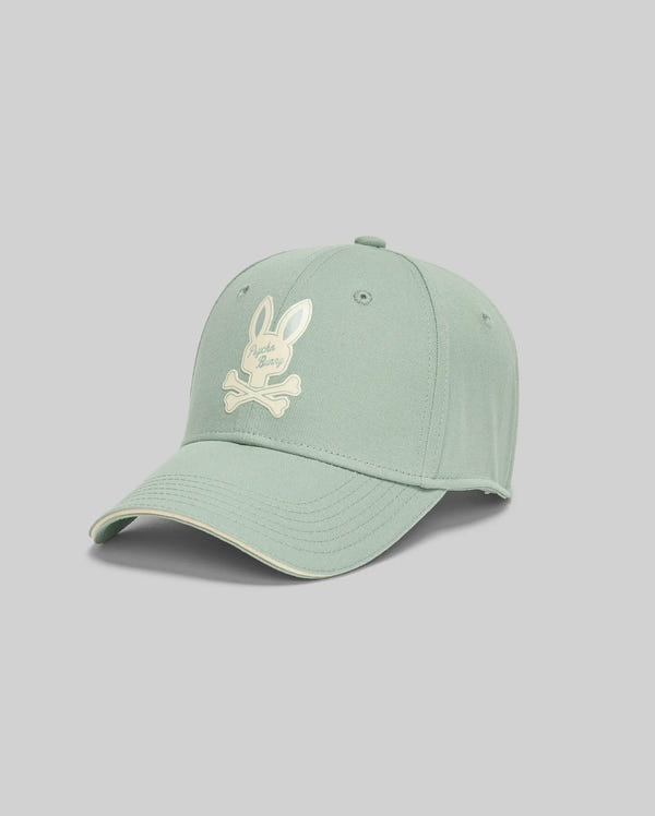 The KIDS DEREK BASEBALL CAP - KO1500008 by Psycho Bunny is a light green premium cotton cap with a bold white embroidered rabbit head and crossed bones logo, shown against a plain gray background.
