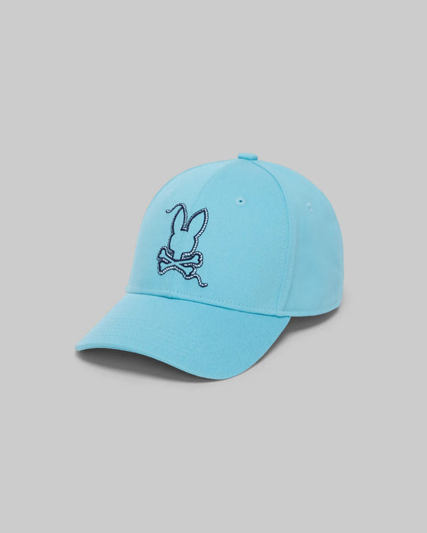 The KIDS CYRUS BASEBALL CAP (KO1500014) by Psycho Bunny features a light blue cotton twill design with a dark blue bunny and crossbones embroidery on the front, shown against a plain gray background.