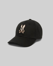 The KIDS WADE BASEBALL CAP - KO1500016 by Psycho Bunny is a black cotton twill cap featuring an embroidered cartoon bunny head over crossed bones on the front, shown against a plain gray background.