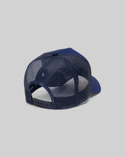The Psycho Bunny KIDS AUGUSTE TRUCKER CAP (KO1500022) in navy blue is shown from the back, featuring an adjustable snapback and curved brim, set against a plain gray background for a classic, comfortable fit.