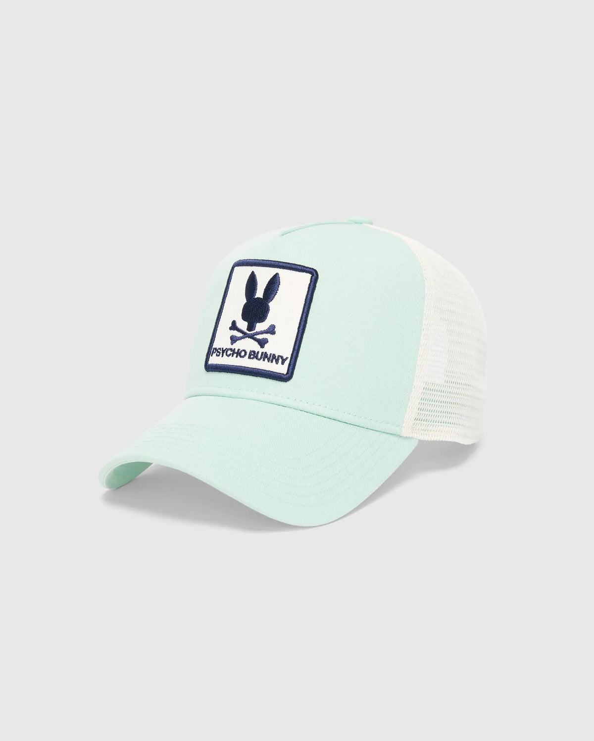 Kids Adamo Bunny Trucker Cap in mint green with white mesh back, featuring a prominent embroidered navy blue and white Psycho Bunny skull logo patch on the front. (2)