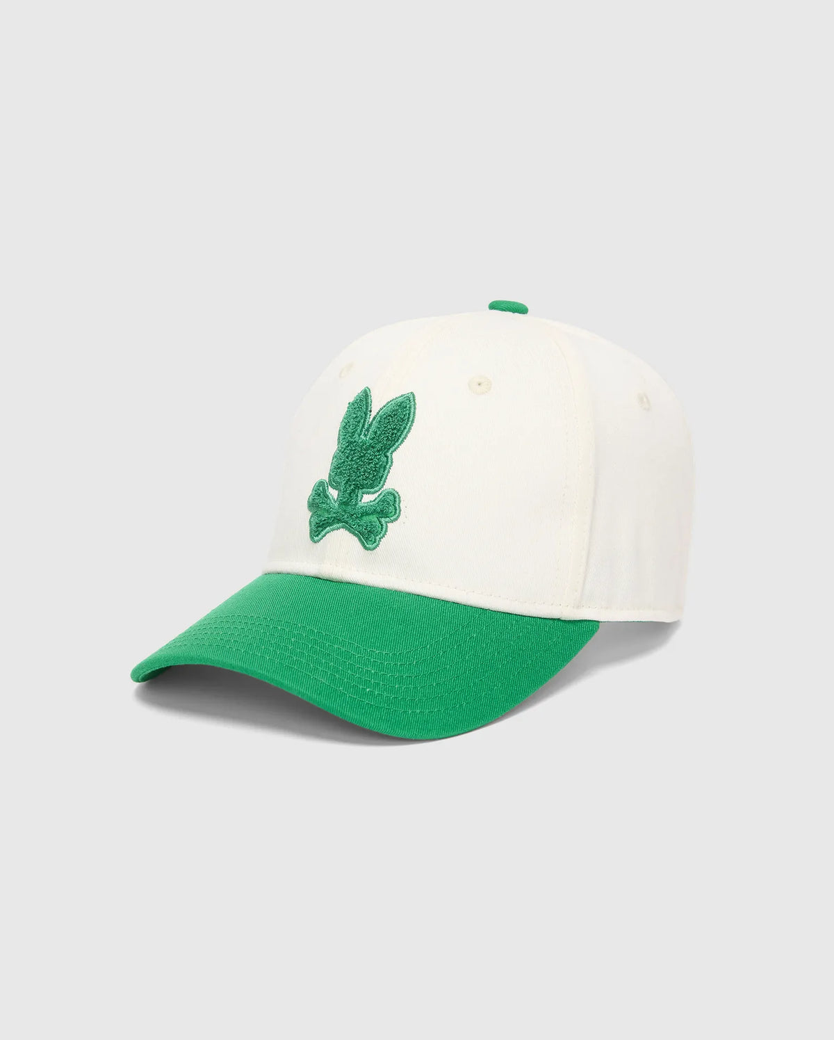Kids Craig Baseball Cap, cream cotton twill crown with a vibrant green brim and top button, featuring a prominent, textured green embroidered Psycho Bunny skull logo on the front. (2)