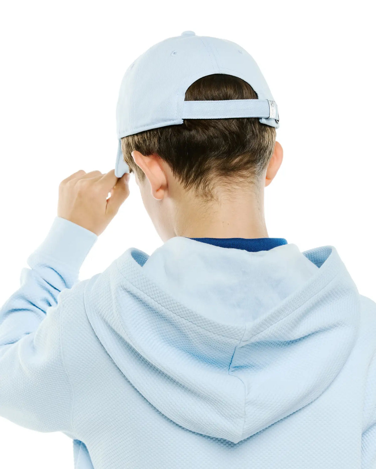 Light blue Kids Jaydon Baseball Cap with adjustable strap and silver buckle, paired with a light blue waffle knit hoodie, revealing a dark blue undershirt collar. (3)