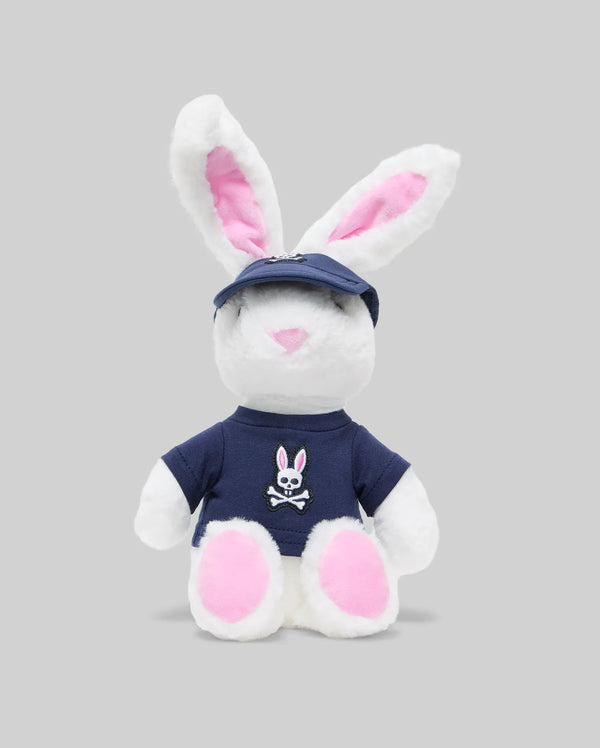 The PSYCHO BUNNY PLUSH - KO1700001 by Psycho Bunny is an ultra-soft bunny with pink ears and feet, a blue cap, and a bunny-and-crossbones shirt, giving it an edgy vibe against a plain gray background.