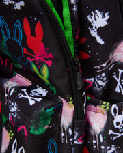 Kids Quintin Backpack in black durable woven fabric, featuring an all-over vibrant graffiti print with Psycho Bunny skull logos, outline bunnies, paint splatters, and crossbones, accented by a bright neon green zipper lining. (2)