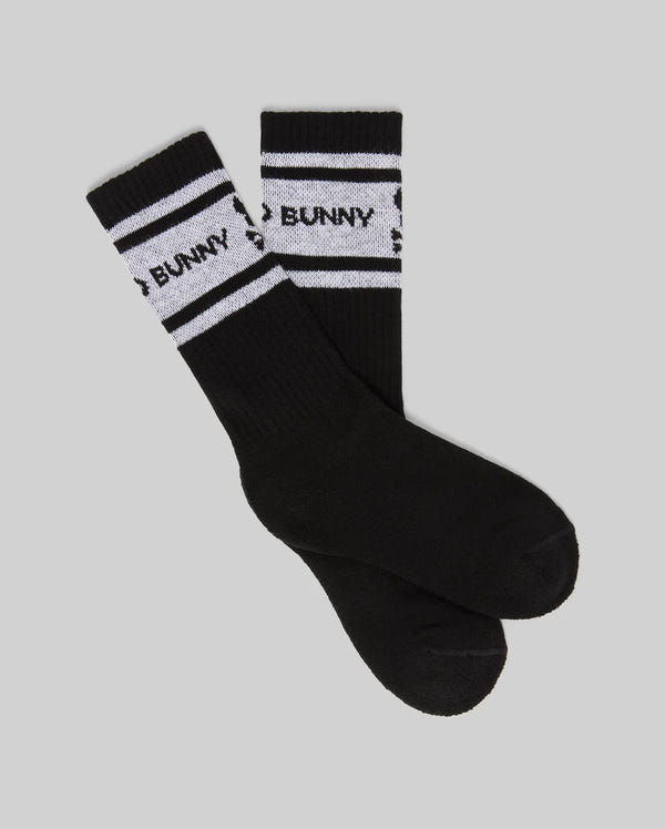 The KIDS 3 PACK SPORT SOCK - KO2200001 by Psycho Bunny features black Pima cotton socks with two white stripes and "BUNNY" written between them, shown on a gray background.