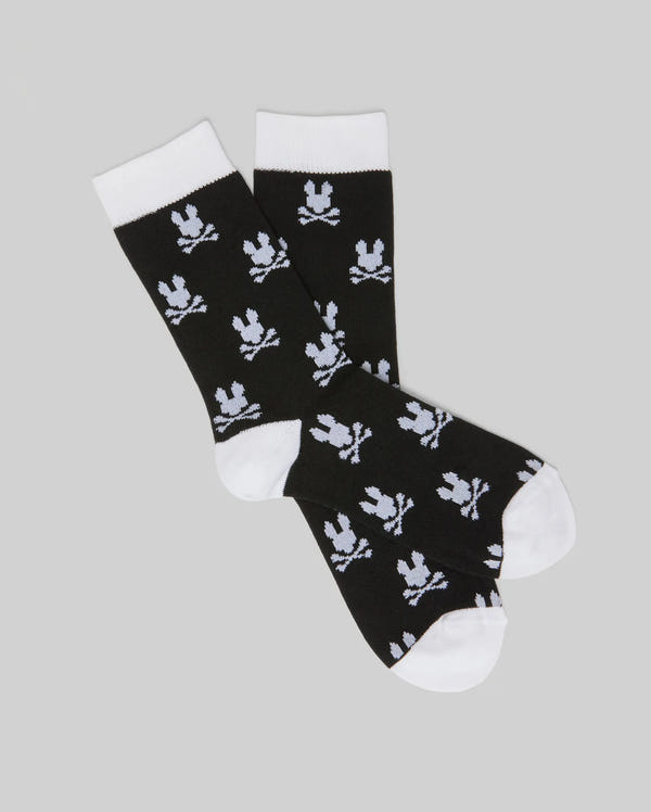 The Psycho Bunny KIDS 2 PACK ALL OVER BUNNY DRESS SOCK (KO2200003) features soft Pima cotton black socks with white heels, toes, and cuffs, plus an allover Bunny skull and crossbones pattern. Shown overlapping on a gray background.