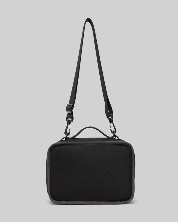 The PSYCHO BUNNY LUNCH BOX - KO2400002 by Psycho Bunny is a black rectangular lunch box featuring an insulated interior, long adjustable strap, and top handle, shown against a plain light gray background.