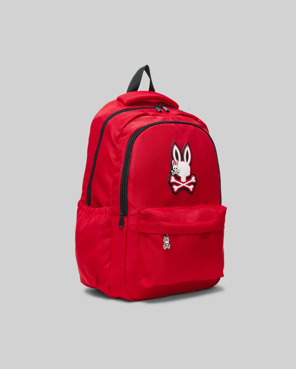 The KIDS PSYCHO BUNNY BACKPACK - KO2400004 by Psycho Bunny is a bright red canvas bag featuring multiple zippered compartments, side pockets, a black handle, and rabbit with crossed bones patches on a light gray background.