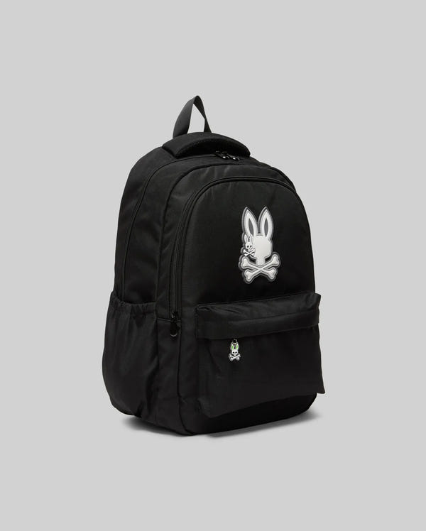The KIDS PSYCHO BUNNY BACKPACK - KO2400004 by Psycho Bunny is a black canvas kids backpack featuring a large white cartoon bunny and crossbones on the front, side pockets, padded straps, and a top handle.
