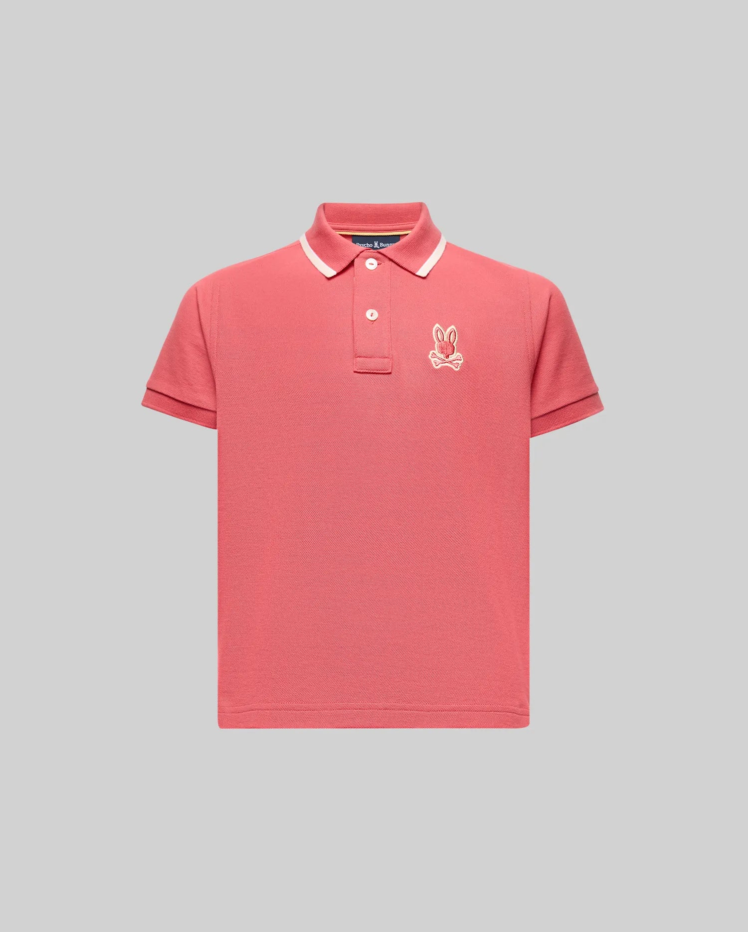 The KIDS FENLEY PIQUE POLO - KT0100023 by Psycho Bunny is a pink short-sleeve polo with a white collar stripe, three buttons, and an embroidered bunny logo on the left chest, made from soft Pima cotton and shown on a plain gray background.