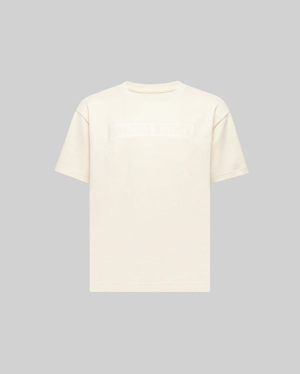 The KIDS ZAYN OVERSIZED GRAPHIC TEE (KT0200001) by Psycho Bunny is a heavyweight, off-white short-sleeve t-shirt with a subtle rectangular graphic across the chest, shown on a light gray background.