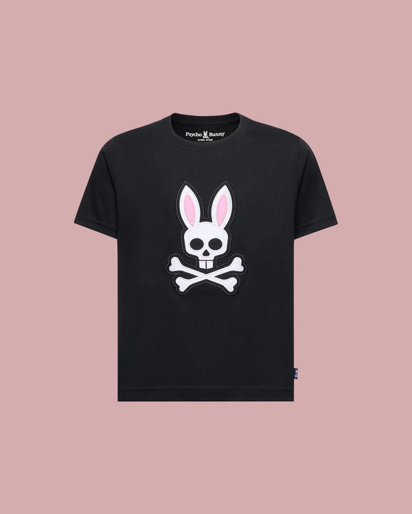 The Psycho Bunny KIDS ARCHIVE BUNNY GRAPHIC TEE (KT0200019) in black features a graphic bunny skull with pink ears and crossbones on the front. Made from Pima cotton, it offers a regular fit for everyday comfort. Displayed on a light pink background.