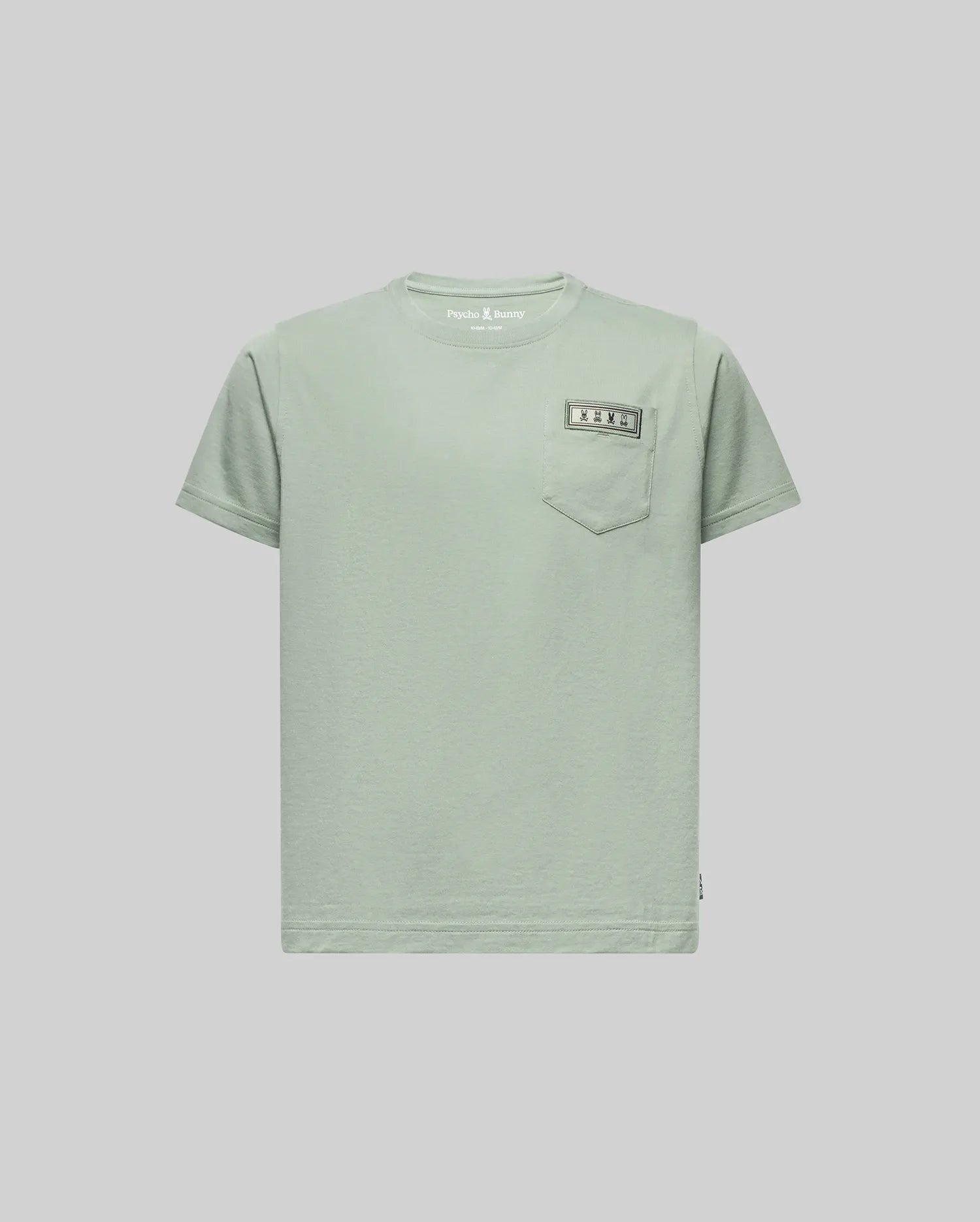 The KIDS AXTON POCKET TEE (KT0200034) by Psycho Bunny is a light green, short-sleeve Pima cotton tee with a left chest pocket and a small sewn rectangular label above it, shown on a plain light gray background.