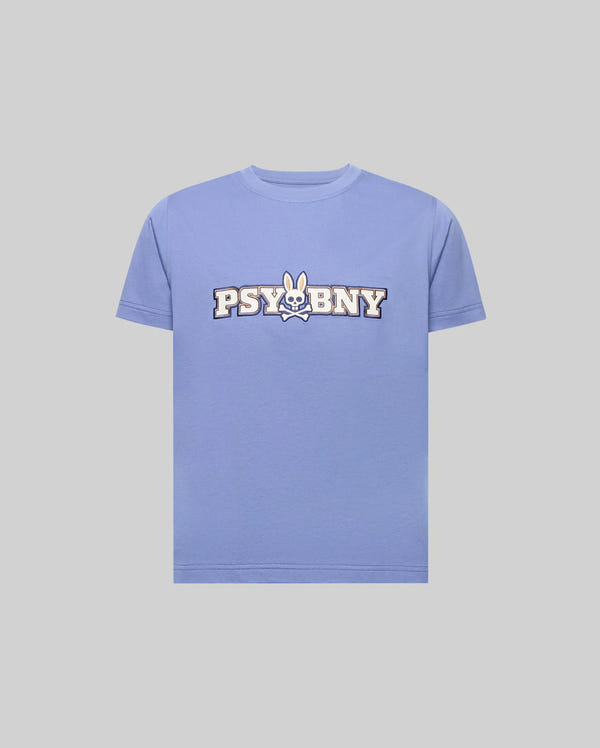 The KIDS WADE GRAPHIC TEE (KT0200055) by Psycho Bunny is a light purple, 100% cotton, regular-fit T-shirt featuring “PSYBNY” in bold with a cartoon bunny face and crossbones replacing the “U,” shown on a plain gray background.