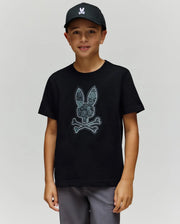 A boy wearing a black KIDS ROWEN BUNNY GRAPHIC TEE (KT0200058) by Psycho Bunny, made from soft Pima cotton, stands against a plain light gray background.