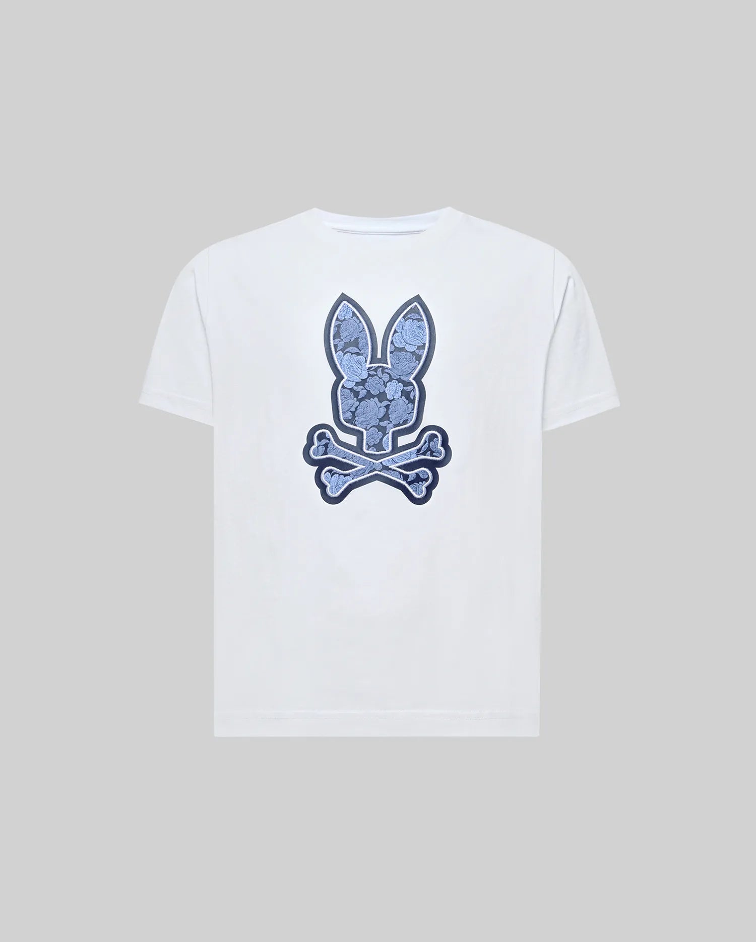 The Psycho Bunny KIDS ROWEN BUNNY GRAPHIC TEE (KT0200058) is a white Pima cotton tee featuring a blue bunny head over crossed bones, giving a playful skull-and-crossbones look against a plain gray background.