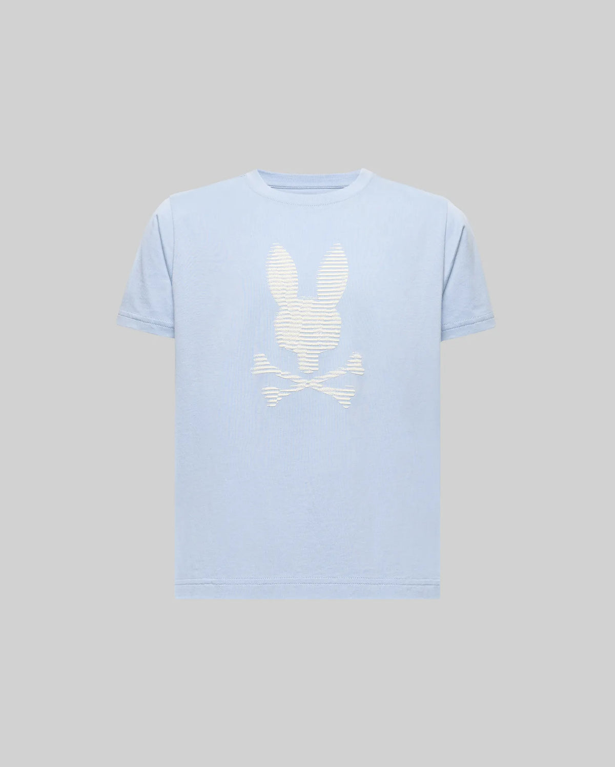 The KIDS GRANT BUNNY GRAPHIC TEE - KT0200061 by Psycho Bunny is a light blue, short-sleeve Pima cotton shirt with a bold white bunny head above crossed bones HD-printed on the front, shown against a plain gray background.