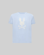 The KIDS GRANT BUNNY GRAPHIC TEE - KT0200061 by Psycho Bunny is a light blue, short-sleeve Pima cotton shirt with a bold white bunny head above crossed bones HD-printed on the front, shown against a plain gray background.