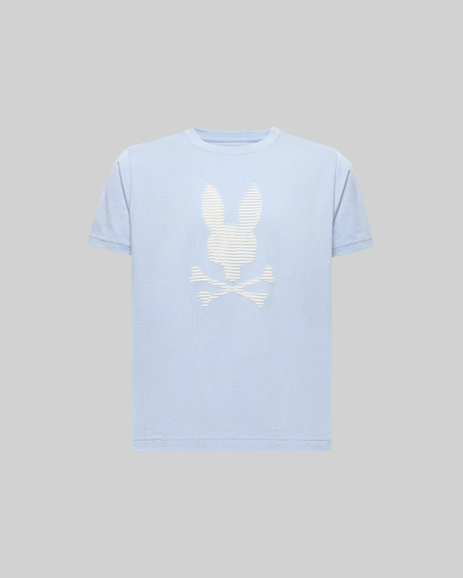 The KIDS GRANT BUNNY GRAPHIC TEE - KT0200061 by Psycho Bunny is a light blue, short-sleeve Pima cotton shirt with a bold white bunny head above crossed bones HD-printed on the front, shown against a plain gray background.