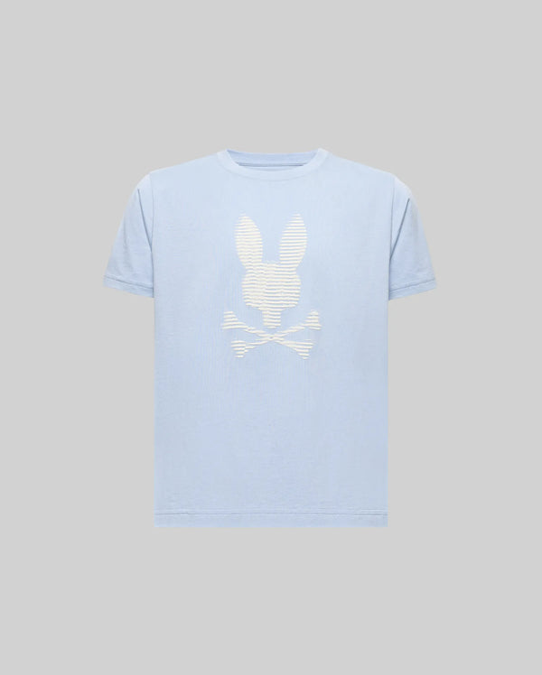 The KIDS GRANT BUNNY GRAPHIC TEE - KT0200061 by Psycho Bunny is a light blue, short-sleeve Pima cotton shirt with a bold white bunny head above crossed bones HD-printed on the front, shown against a plain gray background.