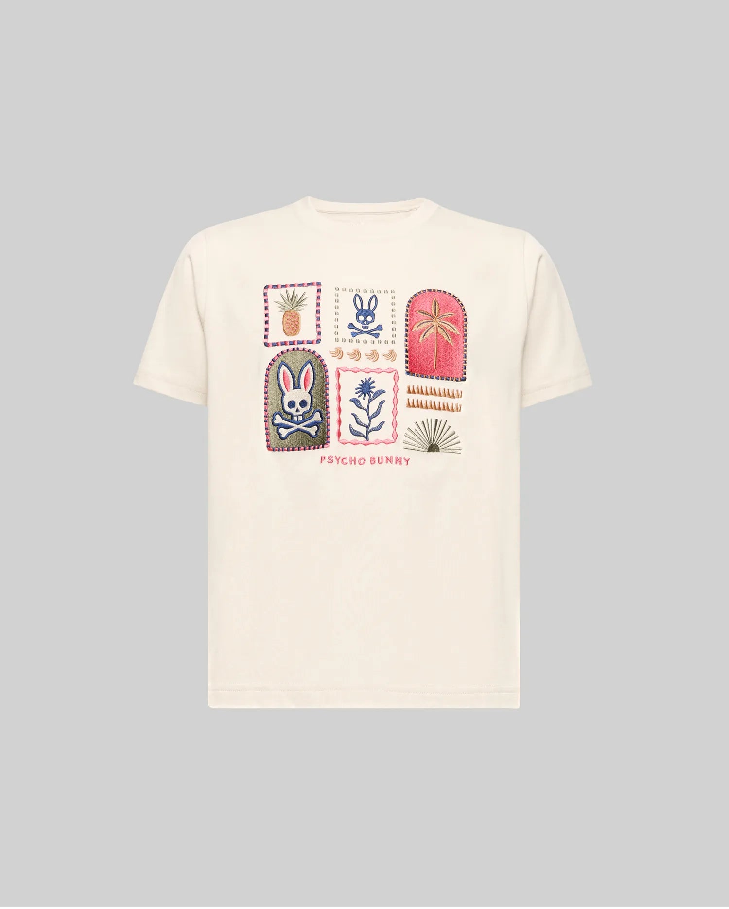 The KIDS SUNDEW GRAPHIC TEE (KT0200092) by Psycho Bunny is a beige Pima cotton shirt with six colorful graphic patches—bunny, flowers, and plants—on the chest and "Psycho Bunny" text beneath. Light gray background shown.