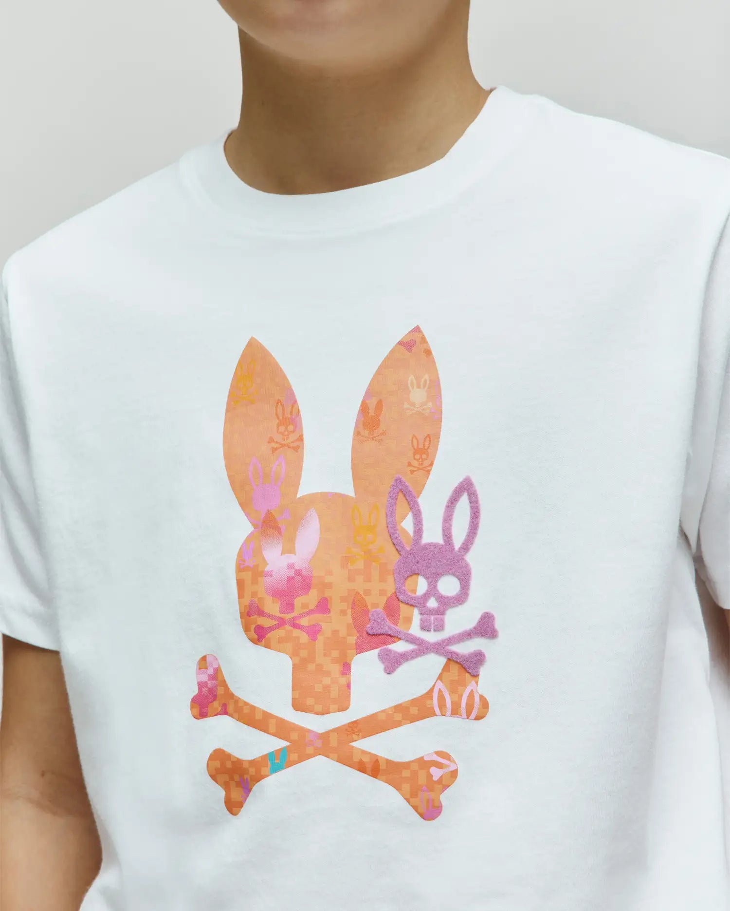 White jersey Kids Van Graphic Tee with a large orange and pink pixelated bunny skull and crossbones graphic, featuring a smaller purple felt bunny skull overlay on the chest.