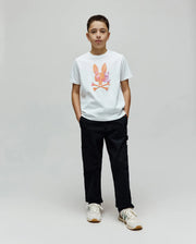 White Kids Van Graphic Tee, a classic fit jersey knit t-shirt featuring a large, colorful watercolor-style Psycho Bunny skull and crossbones graphic on the center chest, paired with black utility pants.