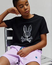 Kids Olivier Graphic Tee in black jersey, featuring a large silver sequin Psycho Bunny skull and crossbones chest graphic, paired with lavender woven shorts displaying a small embroidered teal bunny logo.