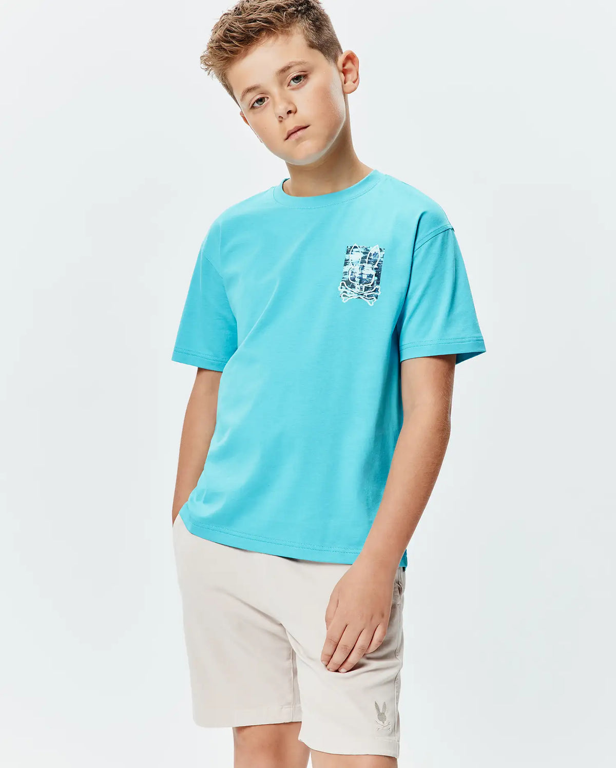 Kids Isaac Relaxed Fit Tee, an aqua blue jersey t-shirt with a relaxed fit and a small, distressed blue and white Psycho Bunny skull graphic on the left chest. (2)