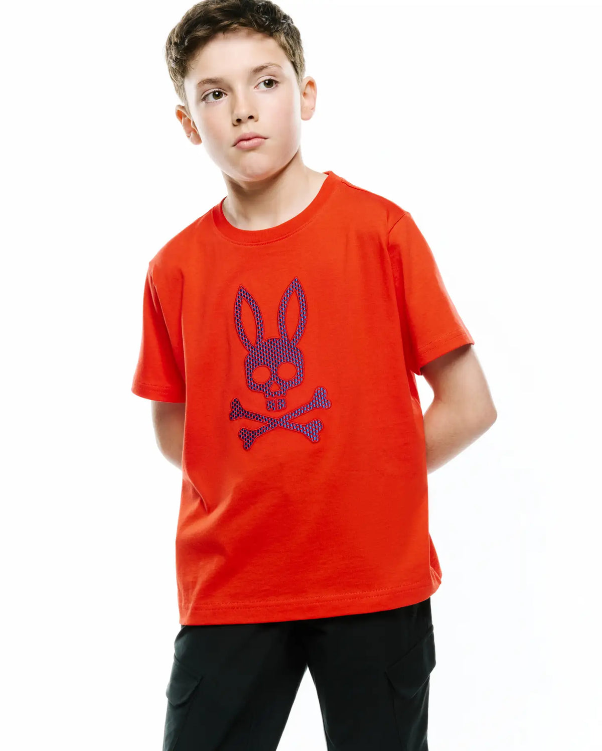 Kids Stan Graphic Tee in vibrant orange jersey knit, featuring a classic fit and a large central chest graphic of the iconic Psycho Bunny skull and crossbones logo in textured purple and blue. (4)