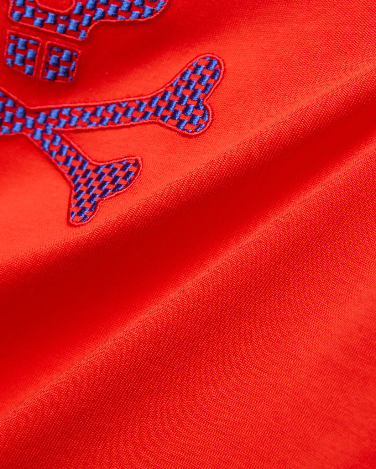 Kids Stan Graphic Tee in bright red jersey knit, showcasing a prominent embroidered Psycho Bunny skull logo with a striking blue checkered pattern. (6)