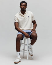 Classic fit cream pique polo shirt with navy tipping on collar and cuffs, featuring a small embroidered Psycho Bunny skull logo on the left chest, paired with light blue textured Mens Koda Oxford Short.