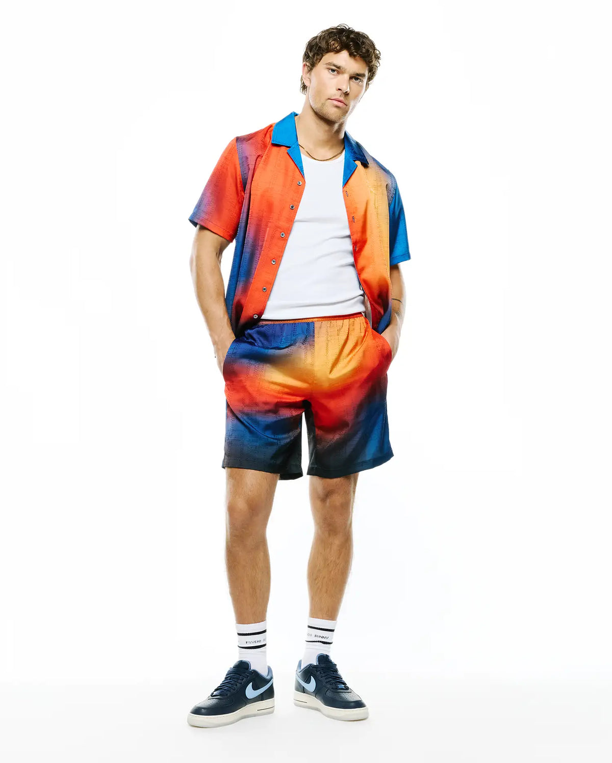 Relaxed fit gradient sunset jacquard short-sleeve shirt with blue collar and matching Mens Zander Jacquard Short, both featuring subtle all-over Psycho Bunny logo pattern, complemented by branded socks. (2)